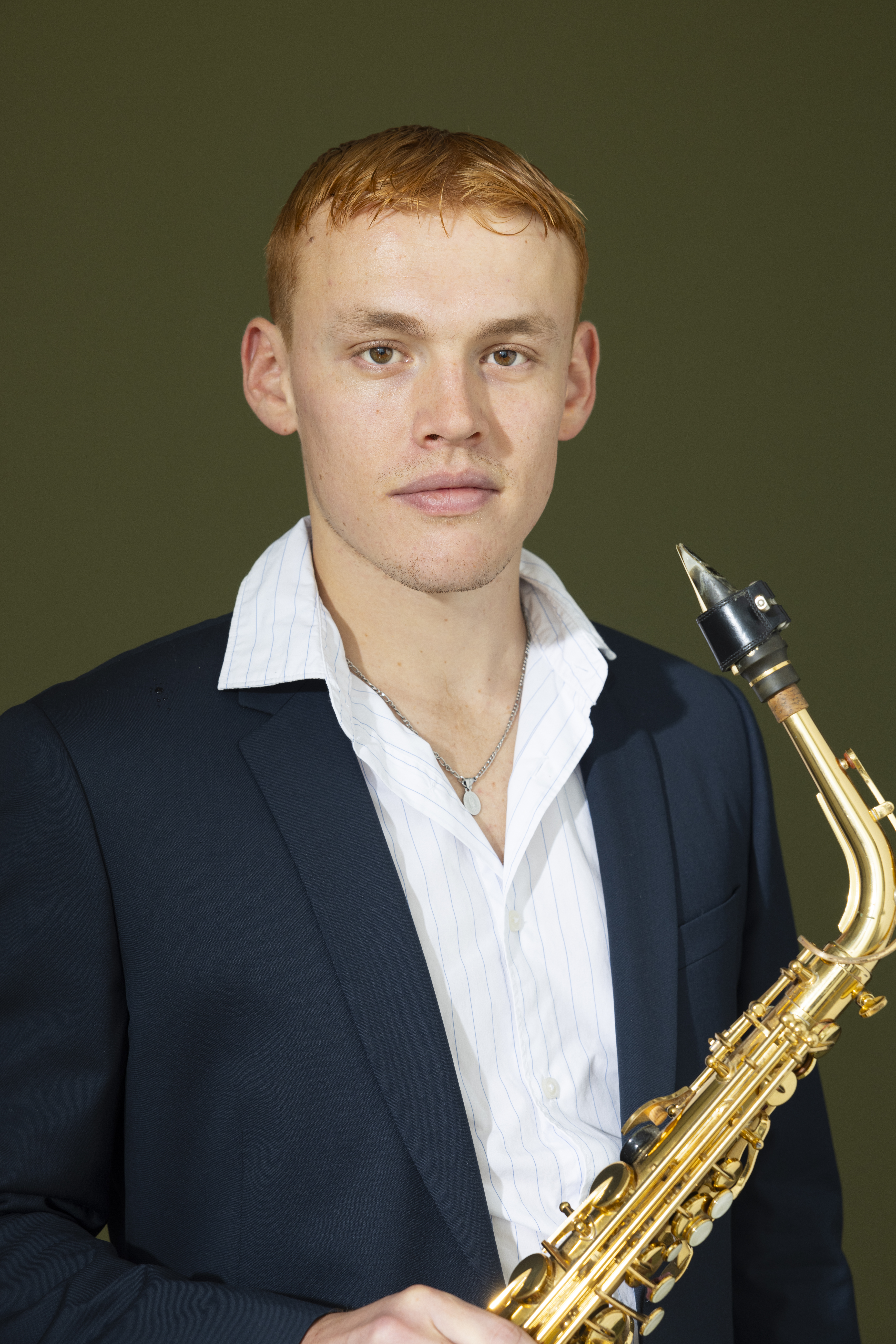 Hélion, saxophoniste et wedding planner Paris, en costume marine avec son saxophone